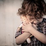 sad little boy hugging a doll